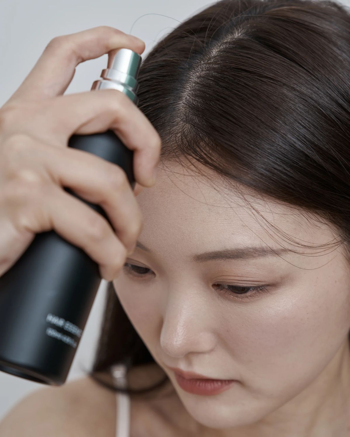 두피 가르마에 토닉을 뿌려 영양 케어를 하는 모습